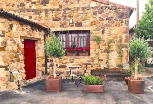 - un bâtiment en pierre avec une table, des chaises et une porte rouge dans l'établissement Casa Rural Zirimiri en Herreros, Soria, à Herreros