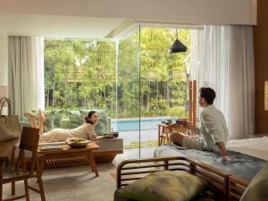 a man sitting in a chair in front of a window at Maya Sanur Resort & Spa in Sanur