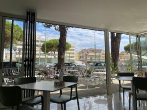 a restaurant with tables and chairs and a large window at Petit Hotel in Caorle