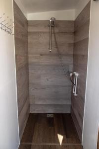 ein Bad mit einer Dusche und einer Holzwand in der Unterkunft Dolina Village Glamping in Zece Hotare