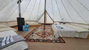 a room with two beds and a rug in a tent at Dolina Village Glamping in Zece Hotare