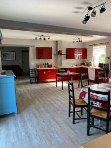 a kitchen with red cabinets and a table and chairs at Gîte proche de Dieppe et bord de mer in Petit-Berneval