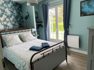 Gîte proche de Dieppe et bord de mer في Petit-Berneval: غرفة نوم بسرير والجدران الزرقاء ونافذة