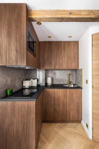 a kitchen with wooden cabinets and a sink at CMG- Charming appartement 2P - Batignolles in Paris