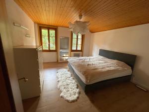 a bedroom with a bed and a wooden ceiling at Magnifique villa avec carnotzet proche de la gare in Romont