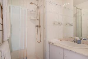 a white bathroom with a shower and a sink at Beaudelaire Center Residence in Paris
