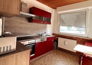 a kitchen with red cabinets and a sink and a window at Ruhige freistehender Bungalow mit Parkplatz in Beckum