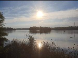 a view of a lake with the sun in the sky at Sycamore Suite is a private retreat with log fire in Eckington