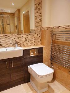 a bathroom with a white toilet and a sink at Sycamore Suite is a private retreat with log fire in Eckington