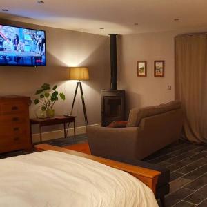 a bedroom with a living room with a fireplace and a tv at Sycamore Suite is a private retreat with log fire in Eckington