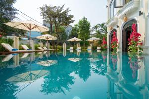 a swimming pool with umbrellas and chairs and a building at Green Tea Villa in Hoi An +19 photos