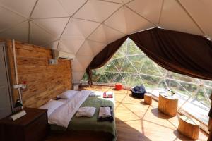 ein Schlafzimmer mit einem Bett und einem großen Fenster in der Unterkunft Elsesi Racha Glamping in Ambrolauri