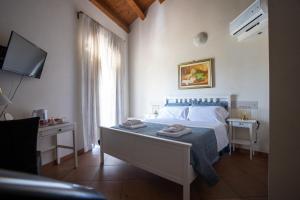 a bedroom with a bed and a television and a window at Bed and Breakfast Terra del Sole Ibla in Ragusa