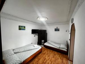 twee bedden in een kamer met witte muren en houten vloeren bij CASA CU LAVANDĂ in Vatra Dornei