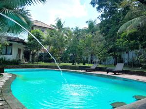 a water fountain in a pool in front of a house at Panorama Hotel in Ubud