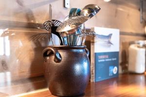 a brown cup filled with utensils on a table at Maybua by May's in Reine