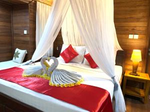 a bedroom with a bed with two swans on it at Bukit Permata Lembongan in Nusa Lembongan
