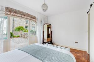 a white bedroom with a large bed and a mirror at The Cow Shed Luxury Barn Moments From Narberth in Pembrokeshire