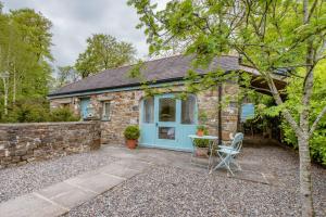a stone cottage with a blue door and a table and chair at The Cow Shed Luxury Barn Moments From Narberth in Pembrokeshire