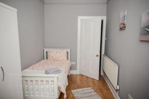 a small white bedroom with a small bed in a room at Bonhill Getaway in Dumbarton
