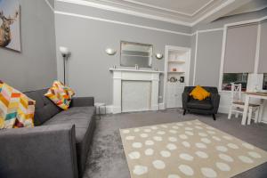 sala de estar con sofá gris y chimenea en Bonhill Getaway, en Dumbarton
