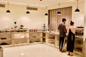 two people standing in a kitchen at Luciana Hotel by BRATUS in Aqaba