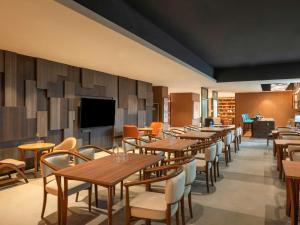 a restaurant with tables and chairs and a flat screen tv at ibis Bengaluru Hebbal - An Accor Brand in Bangalore