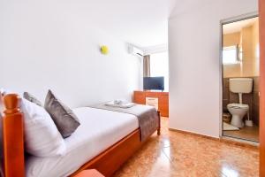 a bedroom with a bed and a bathroom with a mirror at VILA HAVEN - Camere de inchiriat in Costinesti