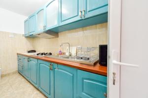 a kitchen with blue cabinets and a sink at VILA HAVEN - Camere de inchiriat in Costinesti +29 photos
