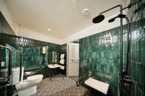 ブローラにあるRoyal Marine Hotelの緑のタイル張りの壁、トイレ2つが付いたバスルーム