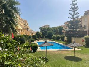 a swimming pool in a yard with two umbrellas at Sea and mountain view Room with pool- Habitación PISO COMPARTIDO para 1 persona in Benalmádena +33 photos