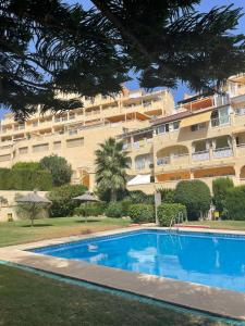 a hotel with a swimming pool in front of a building at Sea and mountain view Room with pool- Habitación PISO COMPARTIDO para 1 persona in Benalmádena