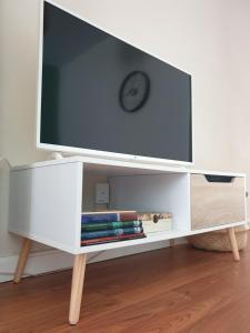 - une télévision sur un support blanc avec une horloge dans l'établissement Apartamento Sabugo, à Avilés