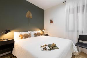 una camera da letto con un letto bianco con due libri sopra di Urban Chill Apartments by Olala Homes a Hospitalet de Llobregat