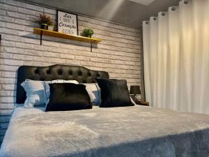 a bedroom with a large bed with a brick wall at Loft Studio 308 no Kobrasol à 7km de Floripa in São José