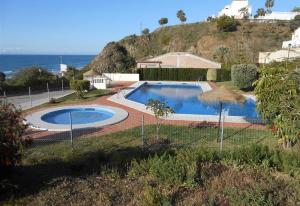 a swimming pool in a yard next to the ocean at Casa Reina Torrox Beach Club in Torrox Costa