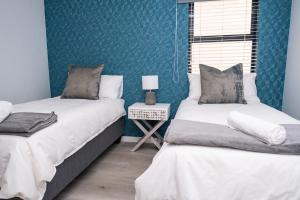 Duas camas num quarto com paredes azuis em Azure 213-Luxury 2 Bedroom Apartment with an Inverter & Battery Backup Power em Big Bay