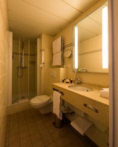 a bathroom with a sink, toilet and mirror at Le Relais Montmartre in Paris