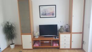 ein Wohnzimmer mit einem TV auf einem Holzschrank in der Unterkunft Zimmer 2 nahe Thoraxklinik - Bad und Küche geteilt in Heidelberg