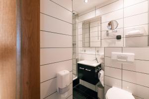 a white bathroom with a toilet and a sink at Hotel Hasenjäger in Einbeck