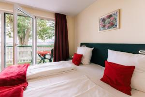 a bedroom with a bed with red and white pillows at Hotel Hasenjäger in Einbeck