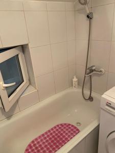 ein Badezimmer mit einer Badewanne und einem rosa Hocker in der Unterkunft Apartmani Petra in Novi Sad