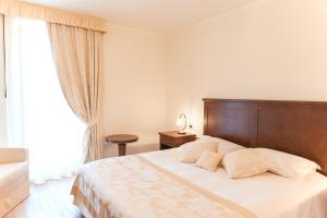 a bedroom with a large bed with a wooden headboard at Hotel & Restaurant Pahor in Doberdò del Lago