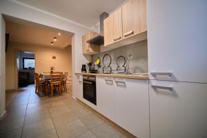 a kitchen with white cabinets and a table and a dining room at Apartament Przy Beczce in Kowary
