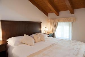 a bedroom with a large white bed and a window at Hotel & Restaurant Pahor in Doberdò del Lago
