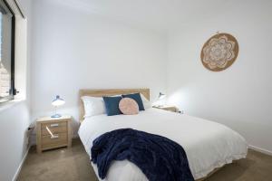 een slaapkamer met een groot wit bed met blauwe kussens bij Villa Mare I 4 Mins to Beach in Culburra Beach