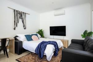 ein Schlafzimmer mit einem Bett, einem Sofa und einem TV in der Unterkunft Villa Mare I 4 Mins to Beach in Culburra Beach
