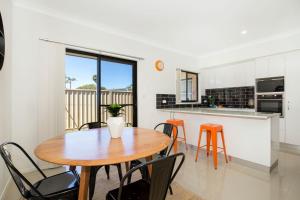 a kitchen and dining room with a wooden table and chairs at Villa Mare I 4 Mins to Beach in Culburra Beach +9 photos