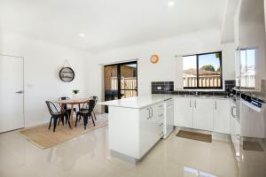 a kitchen with white cabinets and a table with chairs at Villa Mare I 4 Mins to Beach in Culburra Beach
