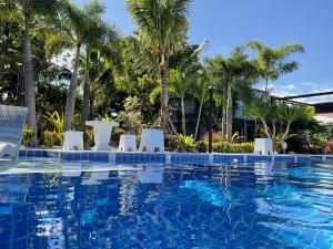 a swimming pool with chairs and palm trees at Sunset resorts and bar in Ban Nong Chaeng